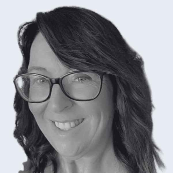 Photo shows a woman with medium length wavy dark hair, wearing dark-rimmed glasses and smiling at the camera. Representing a recruitment agency near you, in Bedford, Buckinghamshire and Northamptonshire.