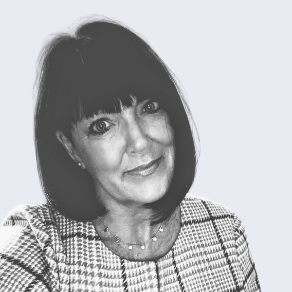 Photo shows a woman with a short dark bob hairstyle, in a tartan-style patterned business dress, smiling at the camera. Representing a recruitment agency near you, in Burton-upon-Trent.