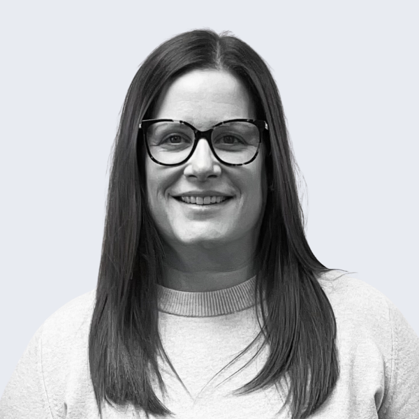 Photo shows a woman with long, straight brown hair, in a light-coloured top, smiling at the camera. Representing a recruitment agency near you, in Prestatyn.