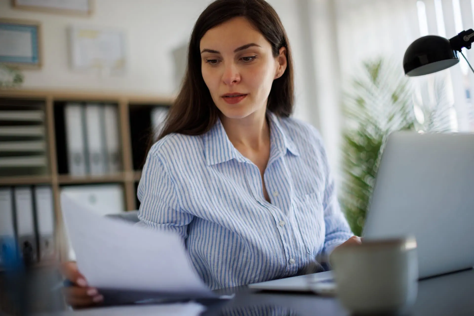 Woman at desk looking at payroll accounting paperwork