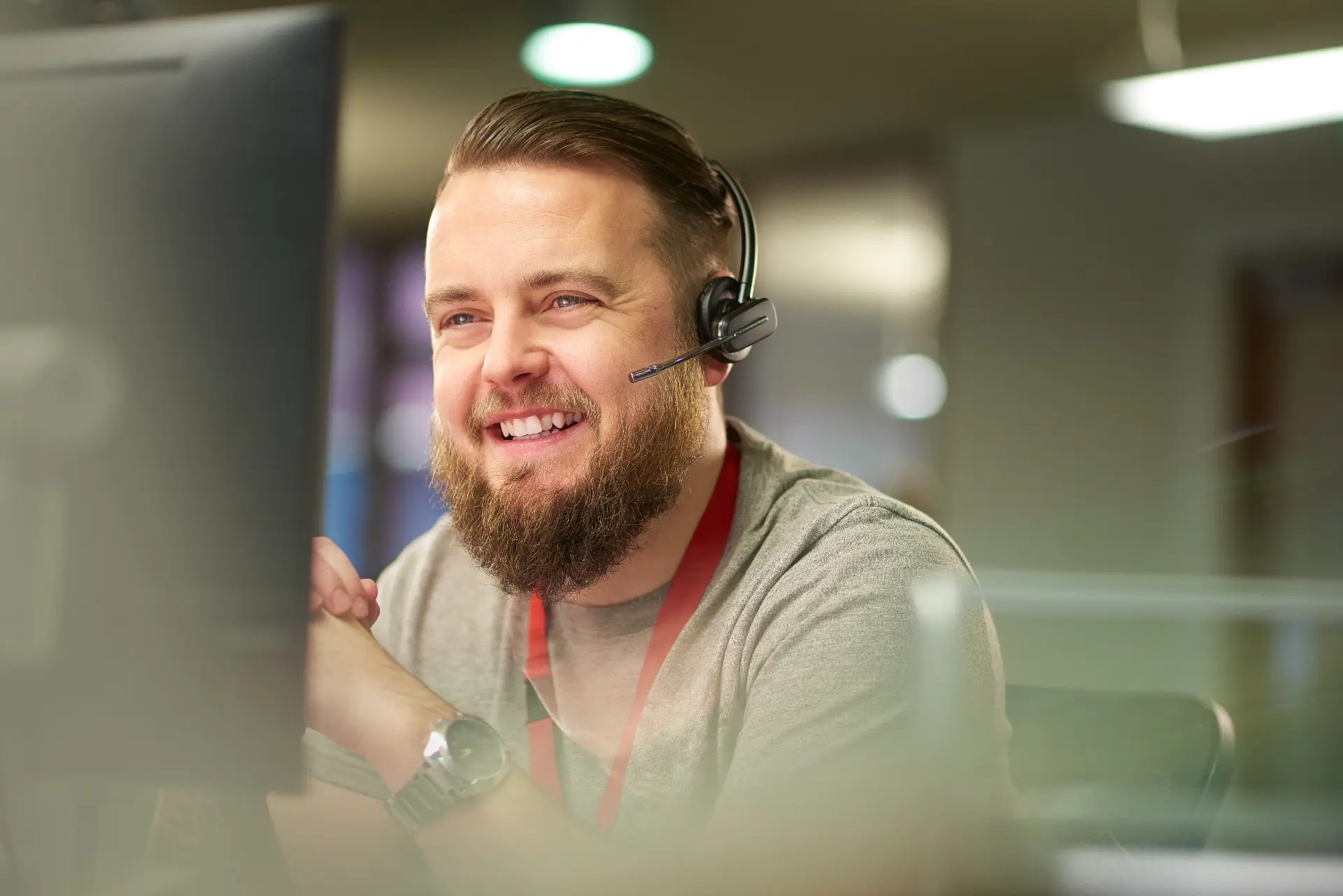 Customer service agent wearing headset and smiling to computer screen 